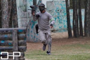 man running and pointing paintball gun